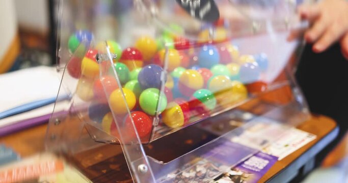 Process of prize drawings, extracting a winning numbers of lottery machine, raffle drum with a bingo balls, bingo machine and winning tickets on event with a host, hands on lottery machine