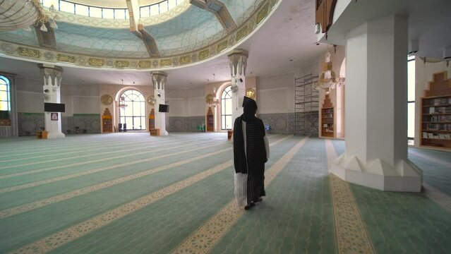 Woman dressed in black and white visiting a Mosque near the Red Sea in Jeddah, Saudi Arabia.  The mosque is called "Al-Rahmah mosque, Saudi Arabia