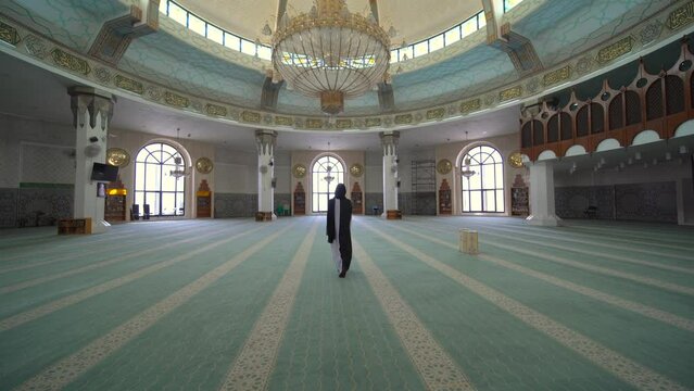 Woman dressed in black and white walking around the Mosque near the Red Sea in Jeddah, Saudi Arabia.  The mosque is called "Al-Rahmah mosque, Saudi Arabia