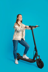 Happy woman with modern electric kick scooter on light blue background