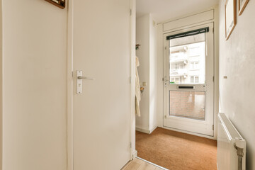 an empty room with white walls and wood trim on the door, there is a small window in the corner