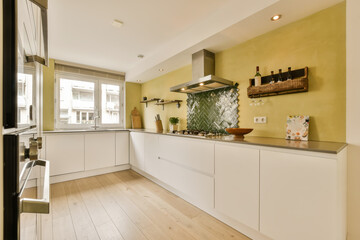a kitchen with white cabinets and wood flooring in the middle part of the room, there is an oven on the wall