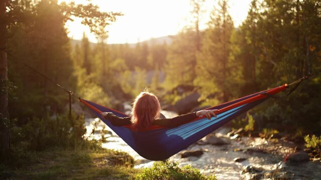 A girl in a hammock near a mountain stream. Calmness, rest and tranquility