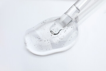 Dripping cosmetic oil from pipette onto light surface, closeup