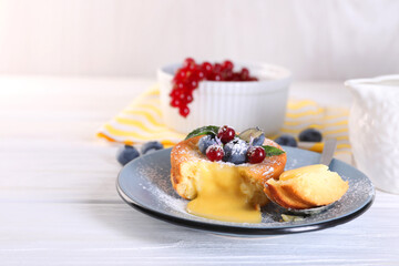 Tasty vanilla fondant with white chocolate and berries on light wooden table. Space for text