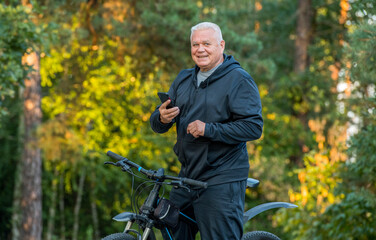 an elderly man with a bicycle and a smartphone spends time in the forest park