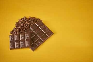 Sensory Delights: A symphony of textures and flavors, with coffee beans and chocolate bars resting on a warm yellow backdrop. The inviting scene offers ample copy space for a delectable story.