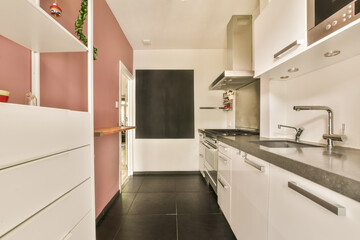 a kitchen with white cabinets and black countertops on the walls, along with pink accent wallpapers...