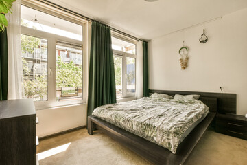 a bedroom with a bed, dresser and large window looking out onto the street outside area in front of...