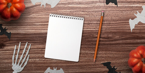 Desk top view, paper bats and Jack O' Lantern pumpkin with a notebook on Halloween day.