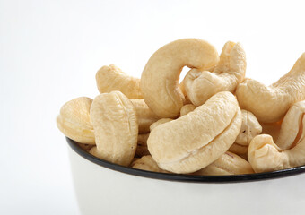 Close up of Fresh tasty cashew nuts in bowl on white background.