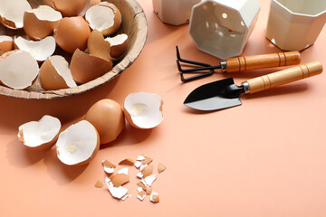 Group of broken egg shells ,plastic flower pot and set of gardening on beige colored background. Recycling kitchen waste, Crushed egg shells for the compost and garden.