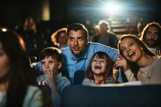 Young family watching a movie and eating popcorn in a movie theater