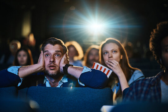 Young couple watching a movie and eating popcorn in a movie theater