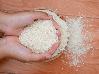 Hand holding wooden bowl filled with rice grains for zakat, concept of zakat in Islamic religion. Muslims help the poor and the needy.