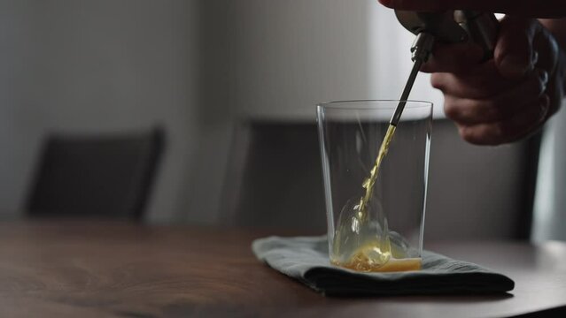 Slow motion pour nitro coffe in tumbler glass on wood table