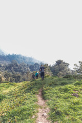 Obraz premium vertical shot of young hiker walking through a rural area on a cloudy day on the slopes of the Turrialba Volcano