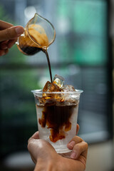 Coffee in plastic cup with ice on blurred coffee shop background