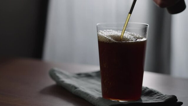 Slow motion pour nitro coffe in tumbler glass on wood table