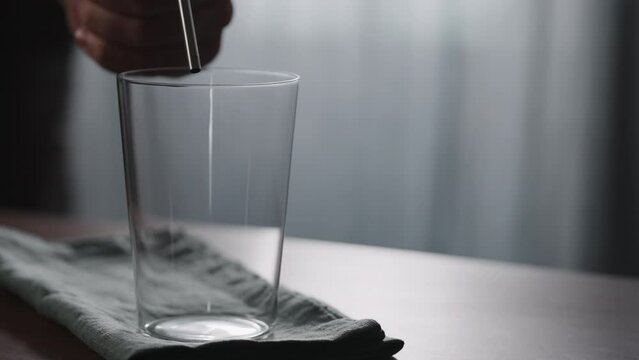 Slow motion pour nitro coffe in tumbler glass on wood table