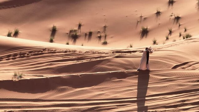 Young bearded man dressed as a shaman dancing on desert sand