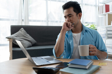 Professional smiling businessman enjoying coffee while working at home office. Sit and relax while using laptop for work in relax, happy.