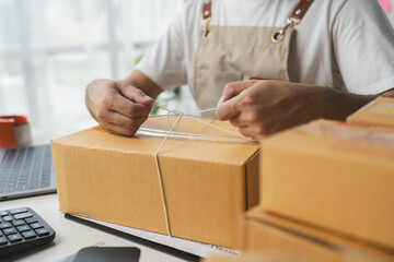 Asian businessmen tie boxes with ropes in preparation for delivery to customers. Young Asian small...