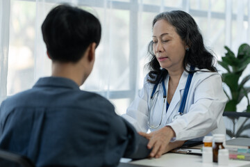 drug concept Health care and treatment. Senior female doctor using a patient's blood pressure monitor for preliminary examination and diagnosis of a patient at a clinic.