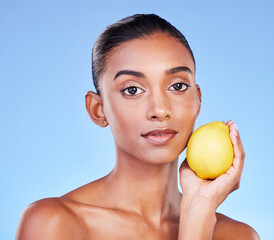 Lemon, portrait or natural skincare of woman in studio for vitamin c benefits, eco cosmetics or nutrition. Face of indian model, healthy beauty or citrus fruit of vegan dermatology on blue background