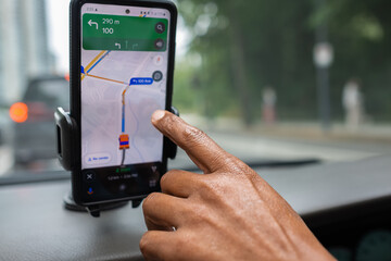 Man drives a car using a GPS navigation system on his mobile phone while driving. Male hand and...