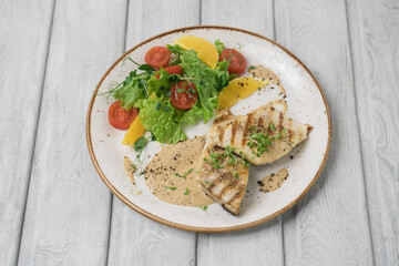Fried fish steak with potatoes and vegetables on table