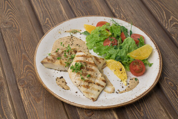 Fried fish steak with potatoes and vegetables on table