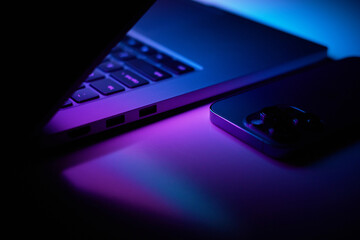 Laptop with smartphone. Neon dark light.