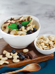 Healthy healthy breakfast. Fruit salad with banana, cashew, blueberry, chocolate and corn flakes. Fitness recipe for healthy balanced breakfast. Still life. Top view.