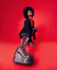 Fashion, boots and portrait of a black woman on a red background in studio to model trendy...