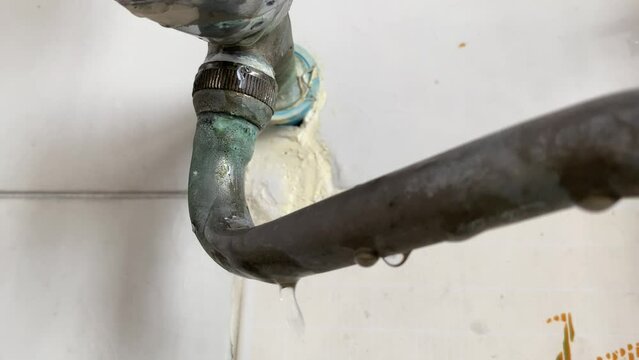 Water leaking from pipe on white wall at home kitchen sink close up view daytime. Home appliance repair and fix concept
