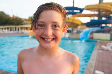 happy 10 year old boy in water amusement park spends summer holidays. joyful smiling wet child...