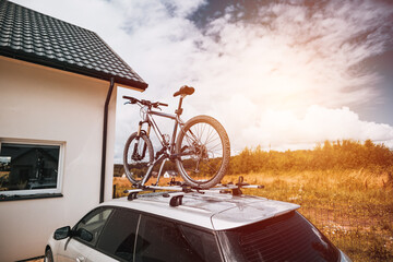 Sport Mountain Bicycle Mounted on Car Roof Against the Evening Sky. Concept of adventures in national park and nature during the summer vacation and holidays.