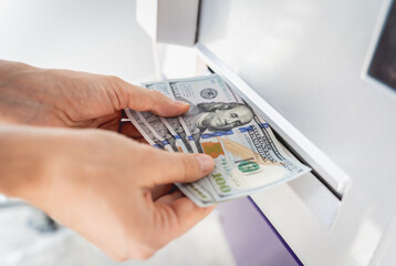Young woman holding money in her hands after withdrawing the cash at the ATM