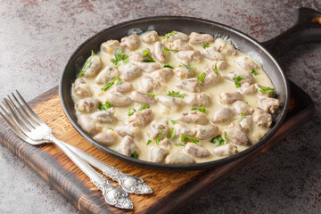 Rustic style stewed chicken hearts in sour cream with aromatic herbs close-up in a plate on the table. Horizontal