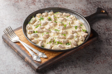 Fried and then stewed chicken hearts in a creamy sauce with aromatic herbs close-up in a plate on the table. Horizontal