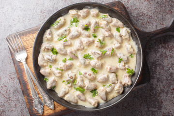 Rustic style stewed chicken hearts in sour cream with aromatic herbs close-up in a plate on the table. Horizontal top view from above