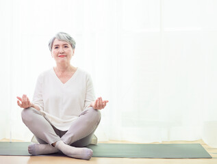 Senior asian woman doing sports at home on a Mat, healthy lifestyle concept.