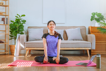 Fototapeta premium Young Asian healthy woman exercising with laptop at home