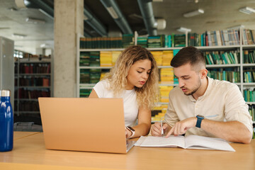 Boy help his girlfriend preparing for exam in public library. Education concept
