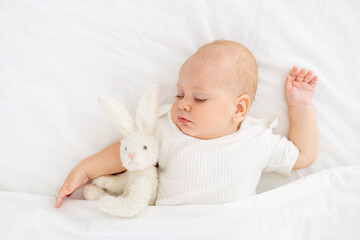 cute little newborn baby sleeping under a blanket hugging a plush bunny, sweet healthy baby sleep in a white crib, a place for text