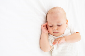 cute little newborn baby sleeps with his hand folded under his cheek, sweet healthy baby sleep in a white crib, a place for text