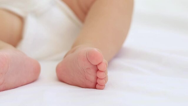baby's small feet on a white bed, a place for text, a close-up of a little baby's feet