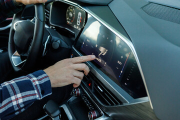 man's hand sets climate control temperature through multimedia touchscreen in SUV