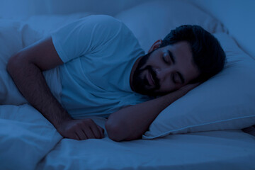 Healthy Sleeping. Portrait of young indian man lying in bed in night
